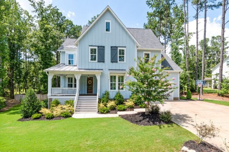 The Cazenovia: light blue farmhouse with a wraparound front porch