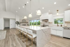 Bright white kitchen with a marble waterfall island and pendant lights