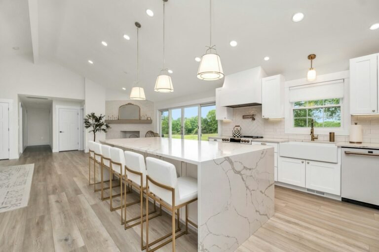 Bright white kitchen with a marble waterfall island and pendant lights