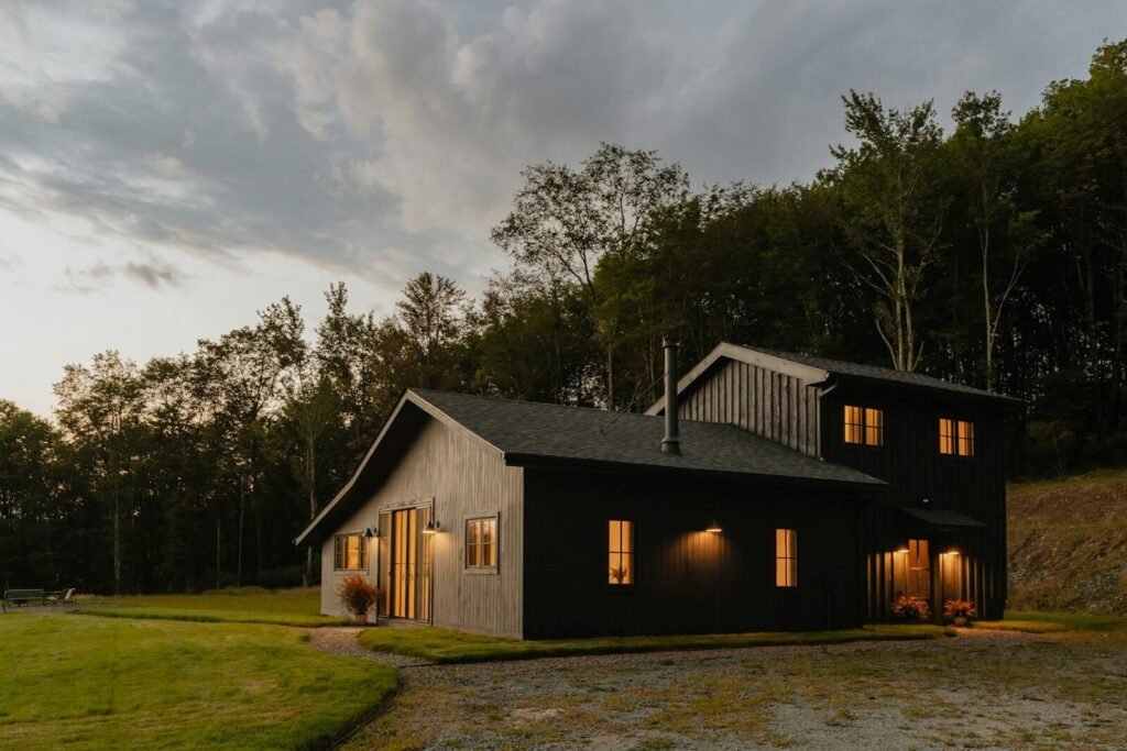 Black board-and-batten modern farmhouse with warm lit windows
