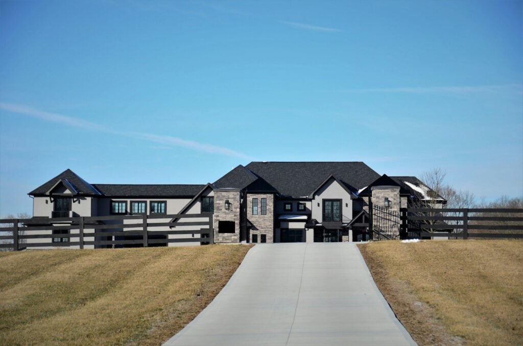 Dark modern home with stone accents and a long concrete driveway