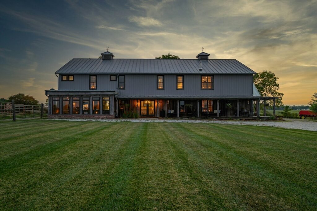 Modern barn-style custom home with a striped lawn at sunset