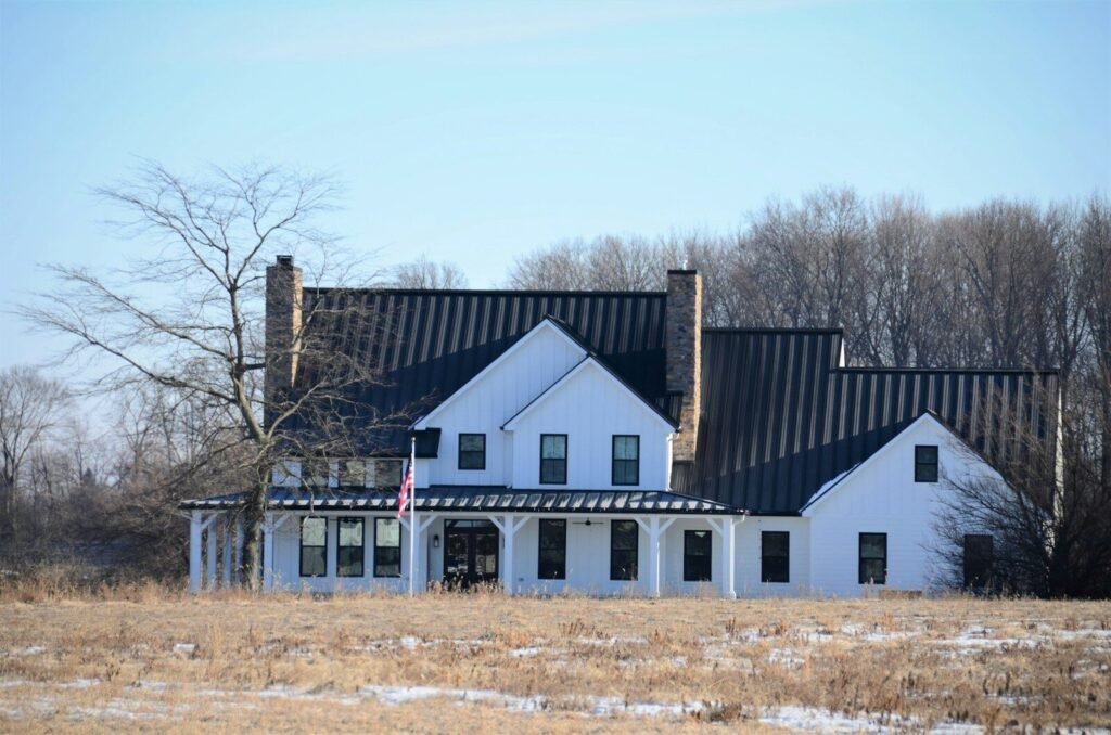 White modern farmhouse with a black metal roof in winter