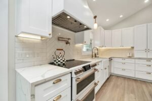White shaker kitchen with quartz counters and a stainless range