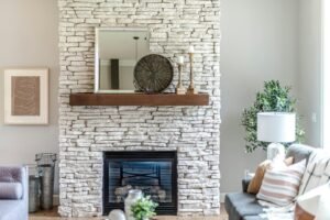Living room with a stacked stone fireplace and wood mantel
