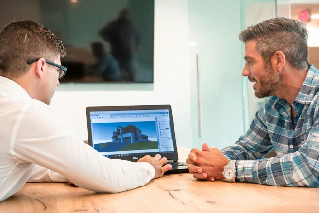 Builder meeting with a homeowner to review a new home design on a laptop